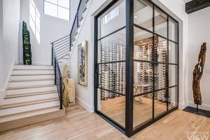 Wine cellar behind glass with black racks and surrounding