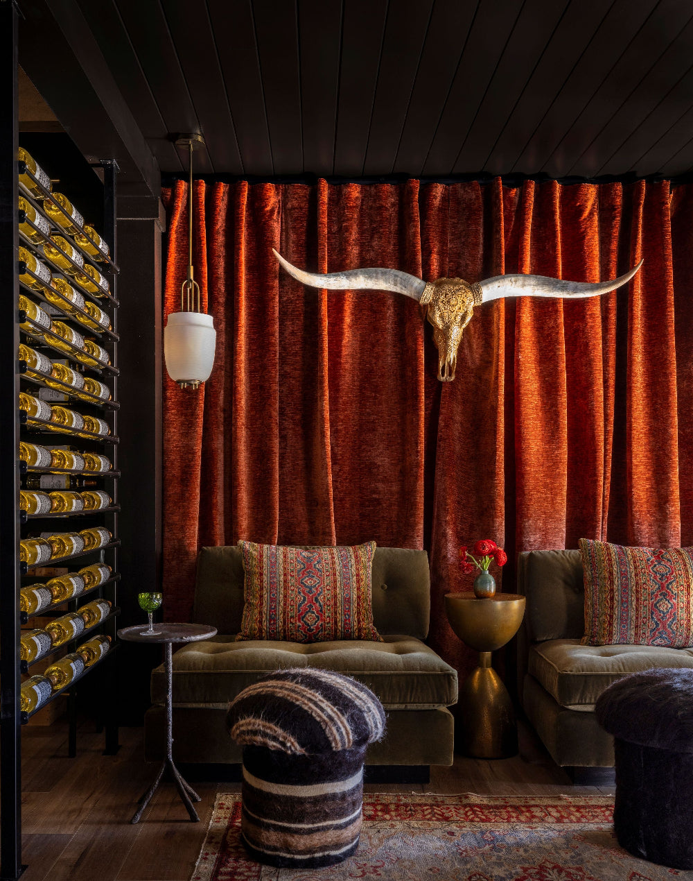 Decorative interior with longhorn skull, orange curtains, and patterned furniture, modern wine rack in home bar