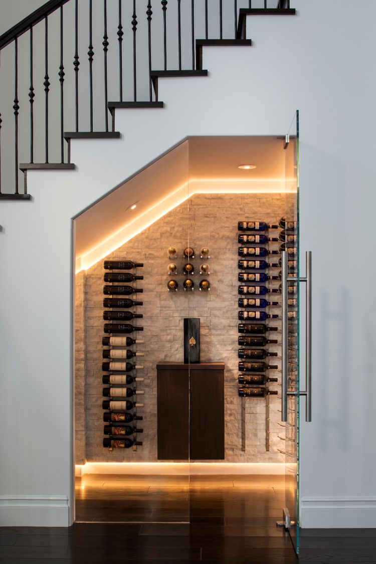 Modern wine cellar with bottles arranged on a wall next to a staircase