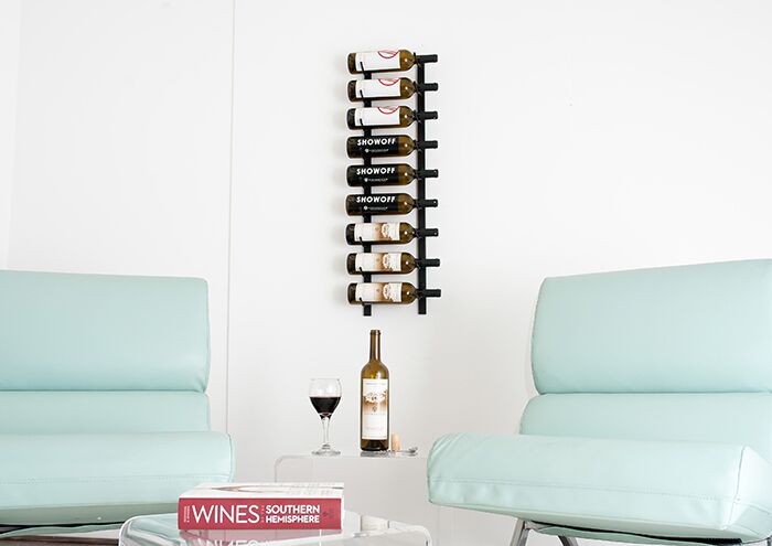Wall mounted wine rack between two chairs with wine bottles